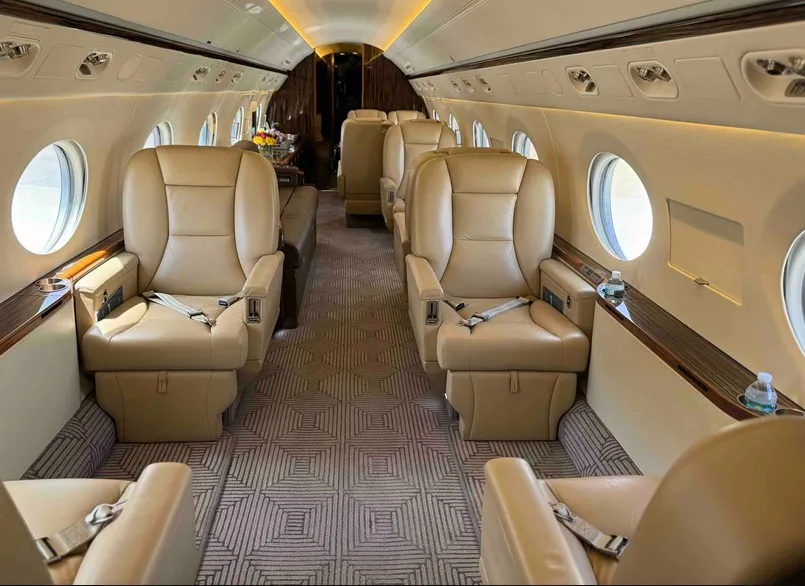 The versatile mid-cabin of the Gulfstream G550, highlighting the comfortable four-place brown leather divan opposite the main club seating area.