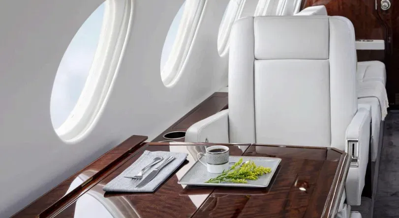 Detail of an executive club seat and polished wood table in the Falcon 50EX, showcasing the comfortable and functional cabin