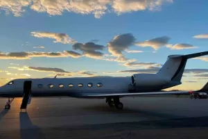 Exterior view of the 2009 Gulfstream G550 on the tarmac at sunset, with its boarding stairs deployed and ready for passengers.