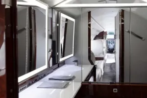 A view from the spacious aft lavatory of the Falcon 50EX, showing the modern vanity, sink, and lighted mirrors reflecting the main cabin